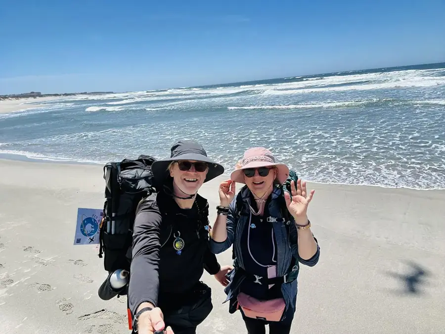Timea und Joachim Krüger mit Rucksäcken direkt am Strand